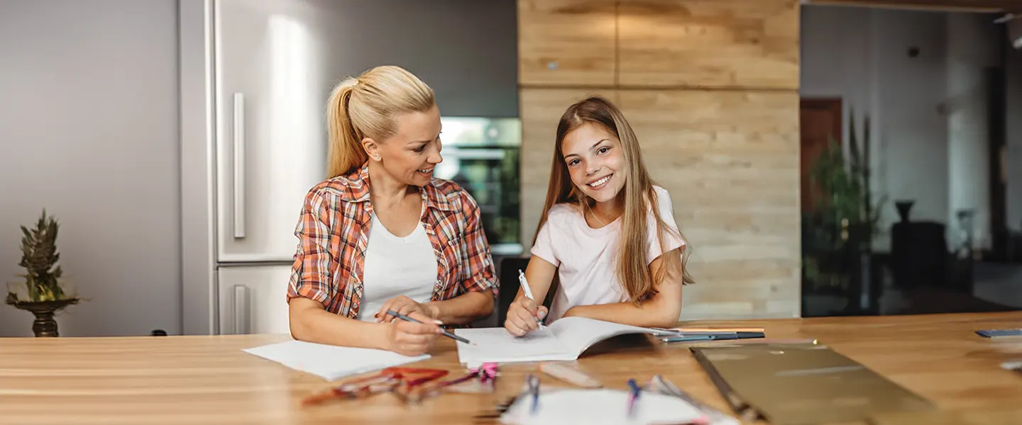 Parent or caregiver with child doing homework at table