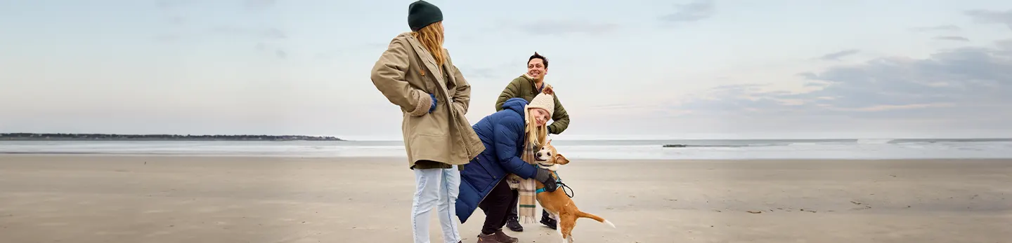 Tara, a real person with narcolepsy with cataplexy taking WAKIX, on a beach with friends and her dog