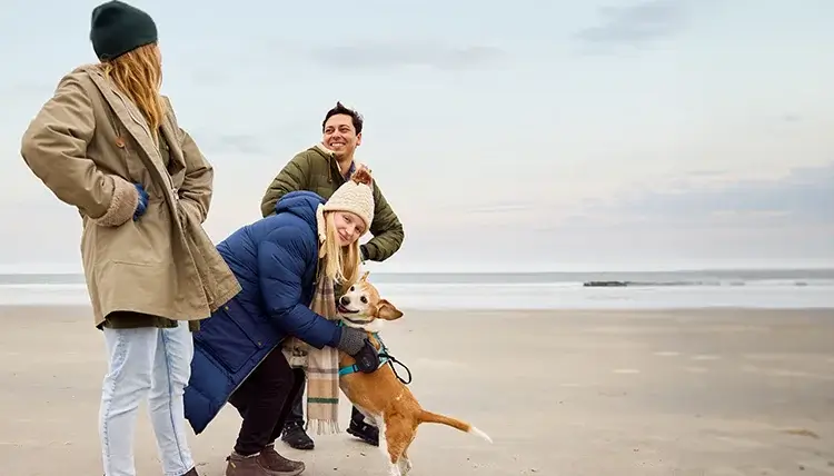 Tara, a real person with narcolepsy with cataplexy taking WAKIX, on a beach with friends and her dog